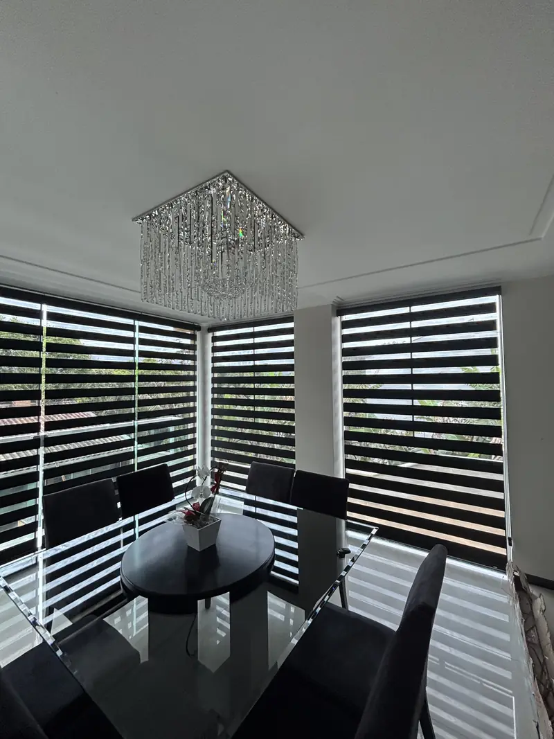 Persiana double vision em canto de vidro na sala de jantar com lustre de cristal