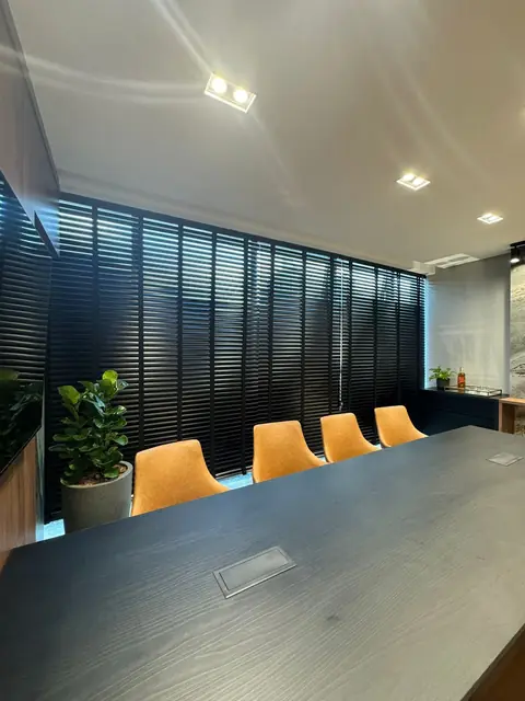 Persiana horizontal de lâminas escuras numa sala de reunião