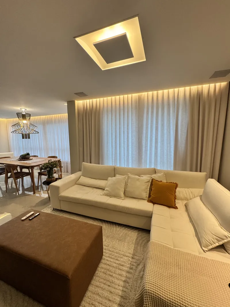 Sala de estar com cortina wave clara do teto ao chão e luz de sanca