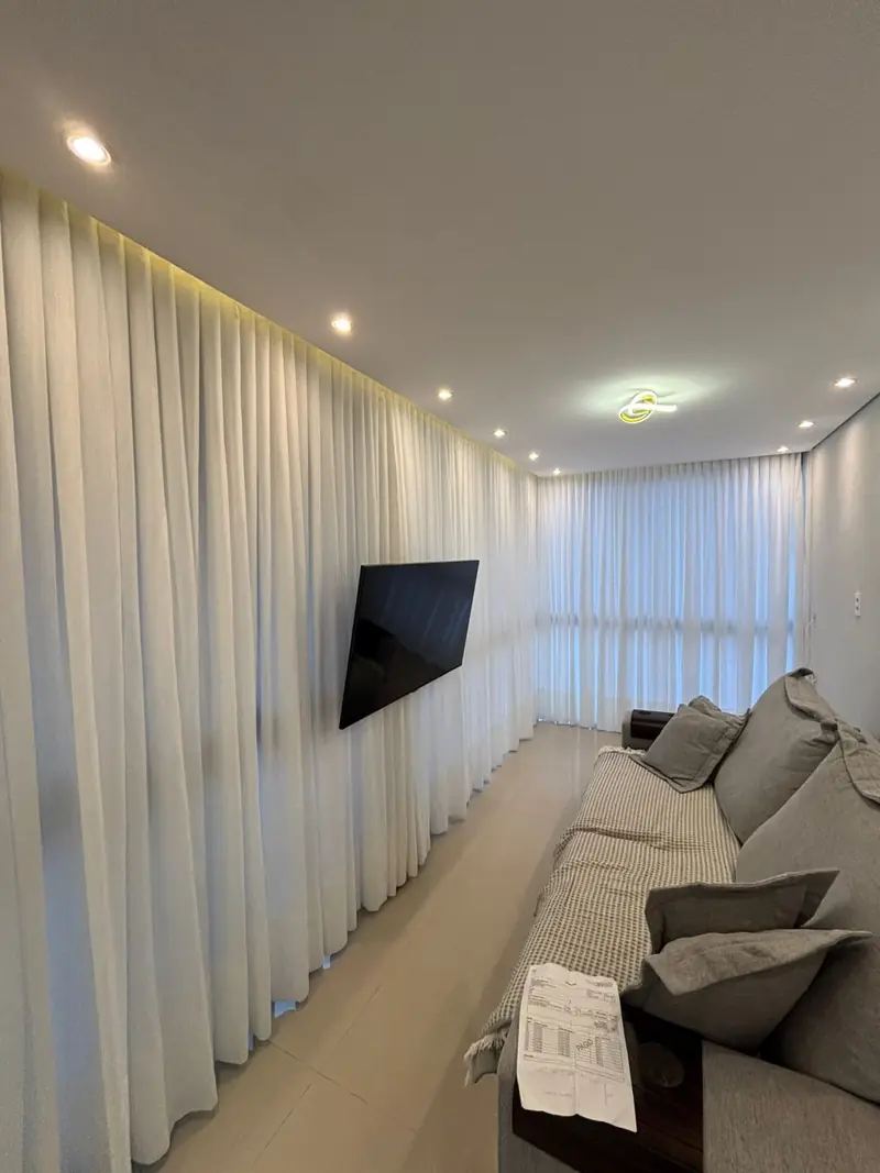 Sala de TV com cortina de linho cobrindo a parede inteira