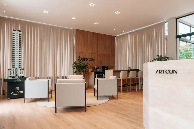 Showroom de construtora com cortinas claras em prega wave